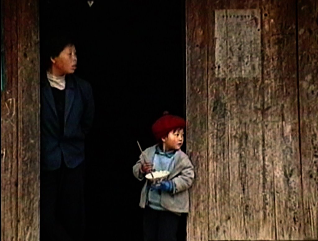 An old photo of two Asian boys, one older and one younger, looking off into the distance