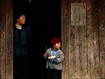 An old photo of two Asian boys, one older and one younger, looking off into the distance